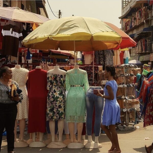 a group of mannequins wearing dresses under a big yellow umbrella