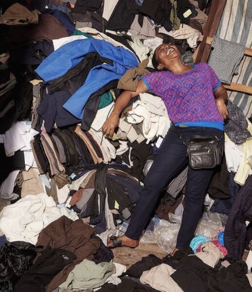 a woman leaning back on a big pile of clothes laughing