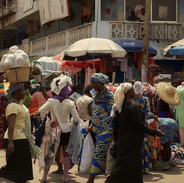 a group of women in a street market with items on their heads