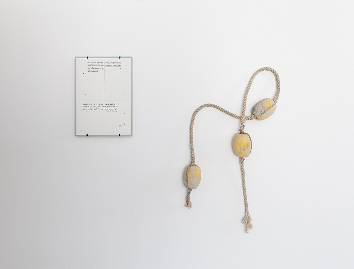 a rope with knots hanging on a wall with a framed piece of paper with writing on it