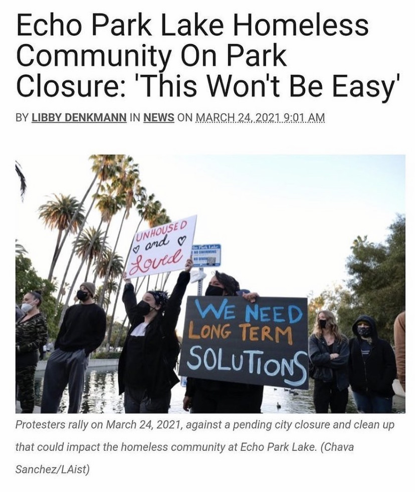 activists holdingn signs in front of echo park lake that read "unhoused and loved" and "we need long term solutions"
