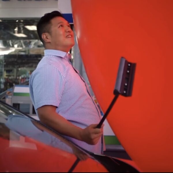 man in a short sleeve button down shirt being squished by an enormous red ballon