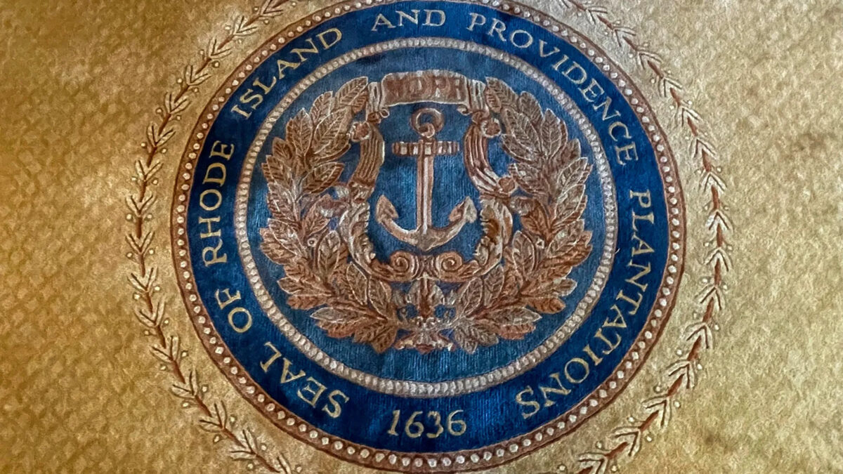 FILE - The state seal with Rhode Island's full former name appears on a rug in the state room on Nov. 4, 2021, at the Rhode Island State House, in Providence, R.I. A new report issued Monday, Aug. 22, 2022, suggests ways Providence can atone for its extensive ties to the transatlantic slave trade and centuries of racism and discrimination by, among other things, establishing home repair funds, launching financial literacy programs and boosting aid to Black and Indigenous organizations. (AP Photo/Jennifer McDermott, File)